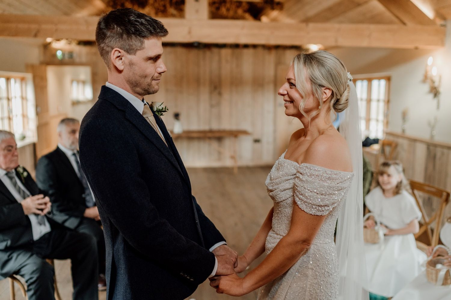 Wedding ceremony moments captured in a bright rustic barn setting with wooden paneled walls.