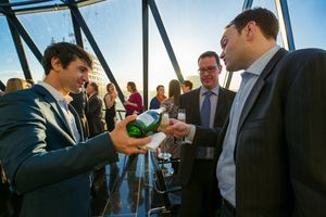 A sequence of candid moments showing people toasting and clinking beer bottles at a social gathering.