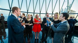 A group of people having a conversation in a modern building with glass windows and city views.