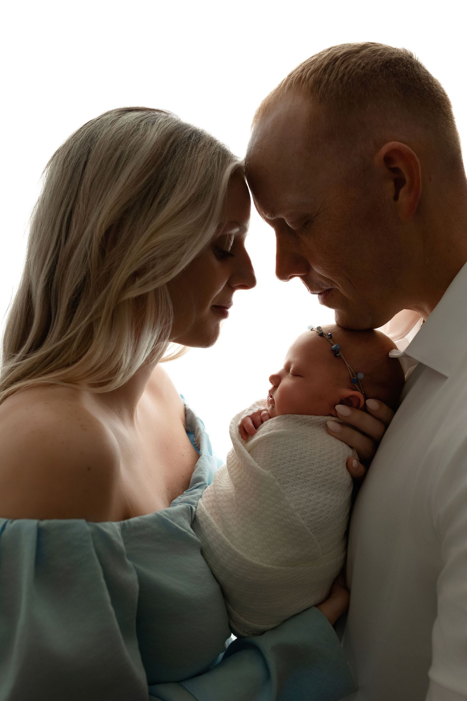 Mom and Dad are tenderly holding the newborn. girl and the photo is backlit. - Greenville SC newborn photographer - Easley SC newborn photo