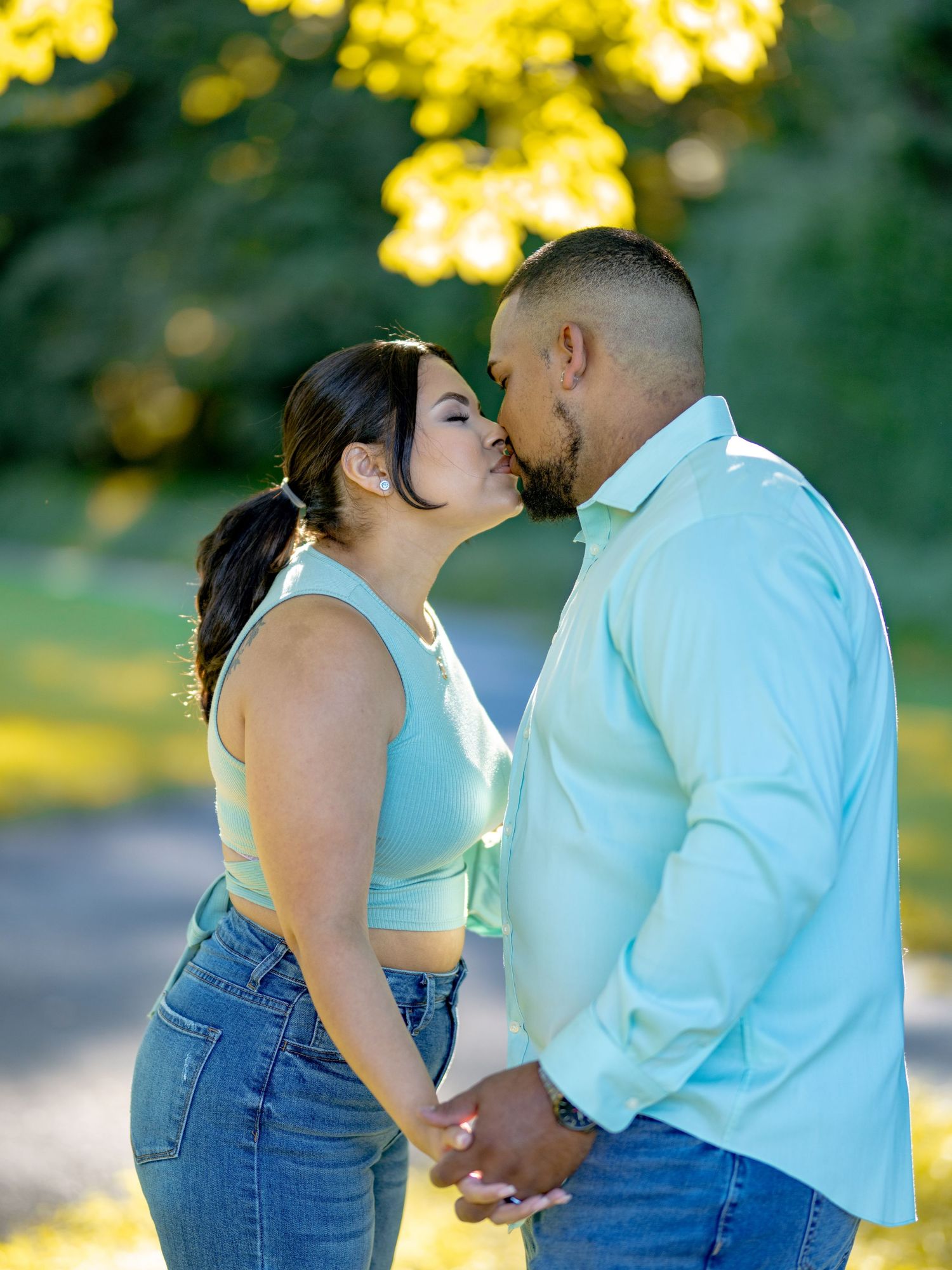 A romantic couple embraces in a park during golden hour with soft sunlight filtering through yellow flowers in the background beautiful enga