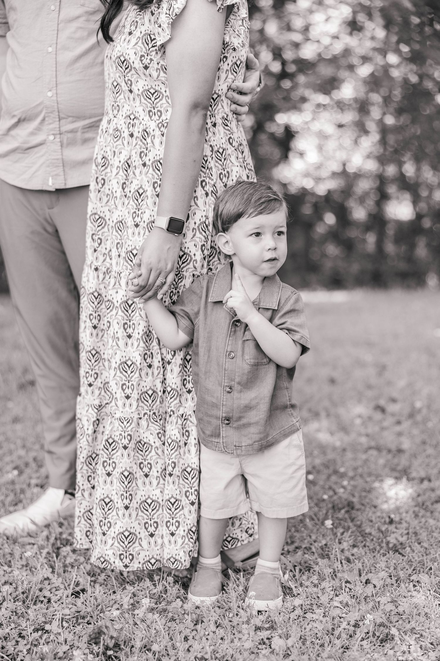 A tender black and white photo series of a parent and child laying in grass while holding ultrasound photos.