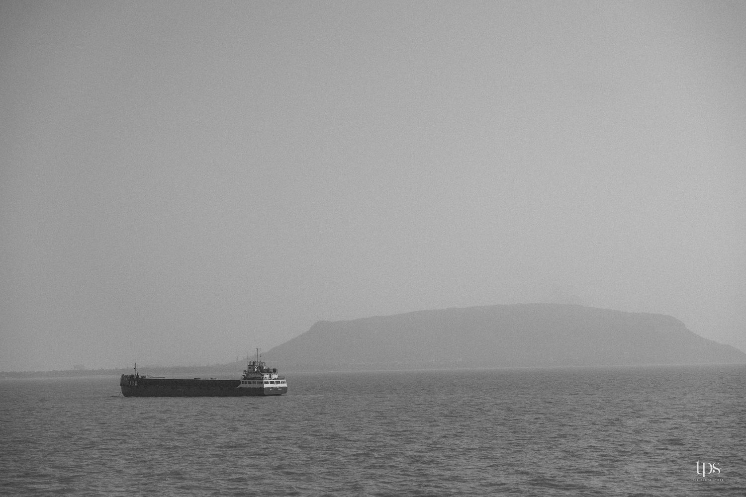 Misty seascape with ships visible on the horizon.