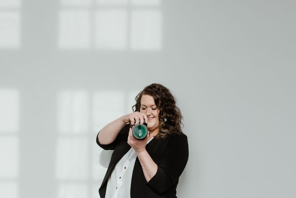 Person in black taking a dramatic bite of a snack against a white wall with window shadows.