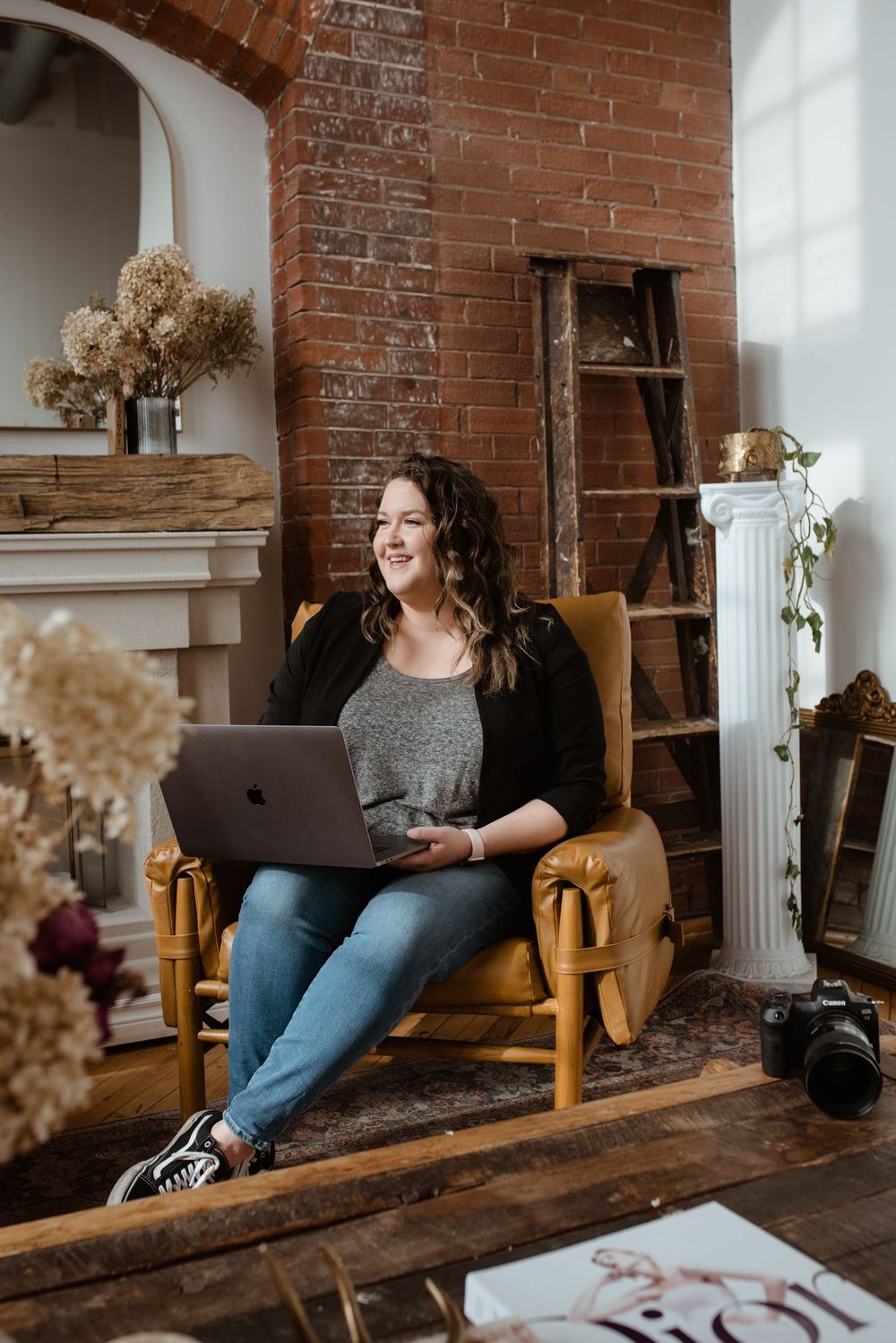 A cozy workspace with exposed brick walls featuring someone working on a laptop while sitting on a wooden bench.