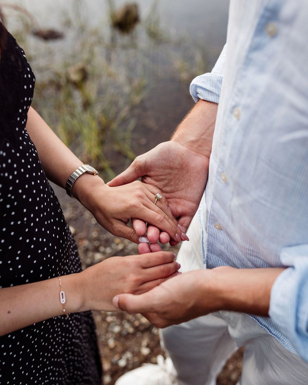 A close-up shot of hands tenderly holding each other while wearing casual attire outdoors.