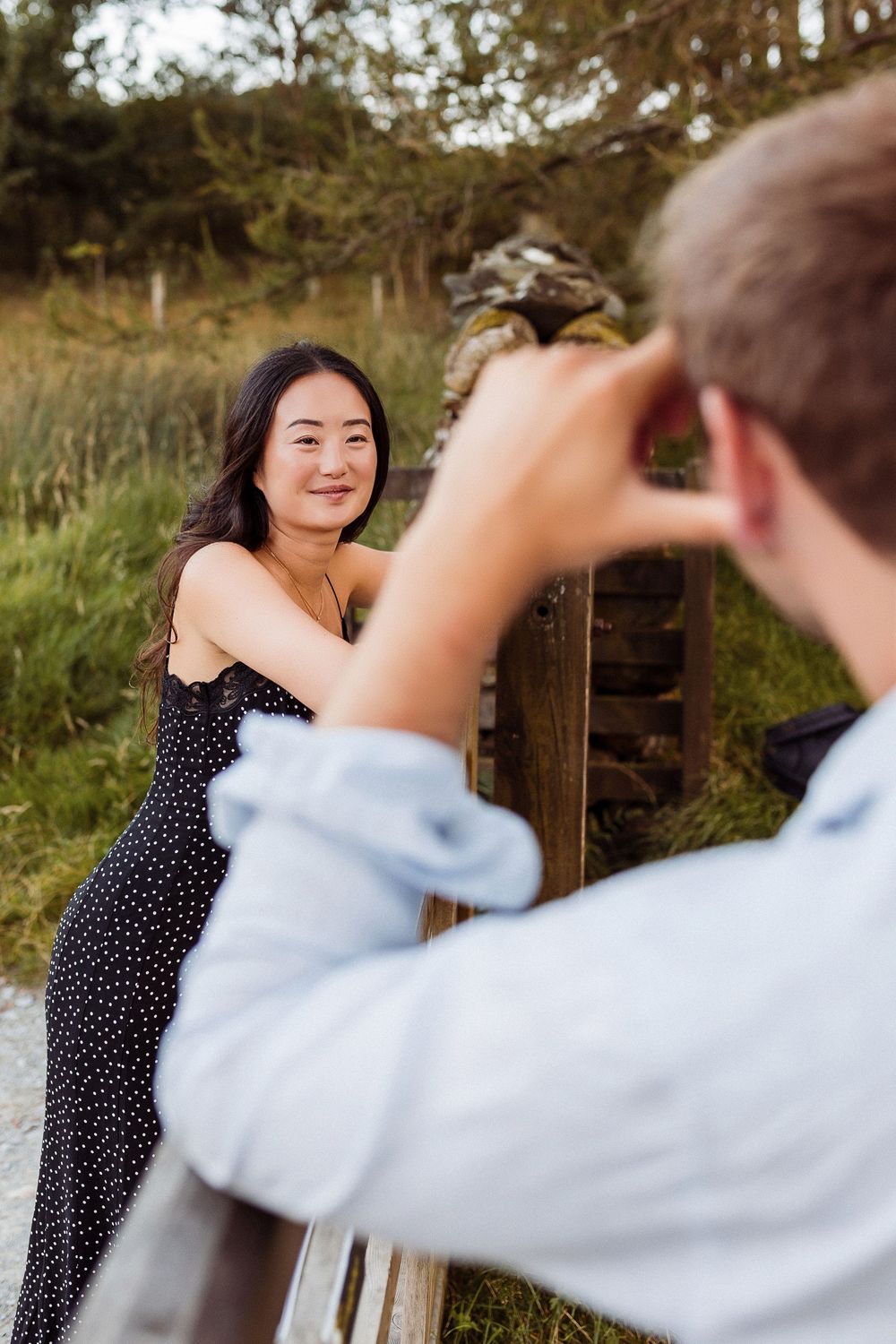 A couple sharing a playful moment outdoors as they pose on wooden steps in a natural setting.