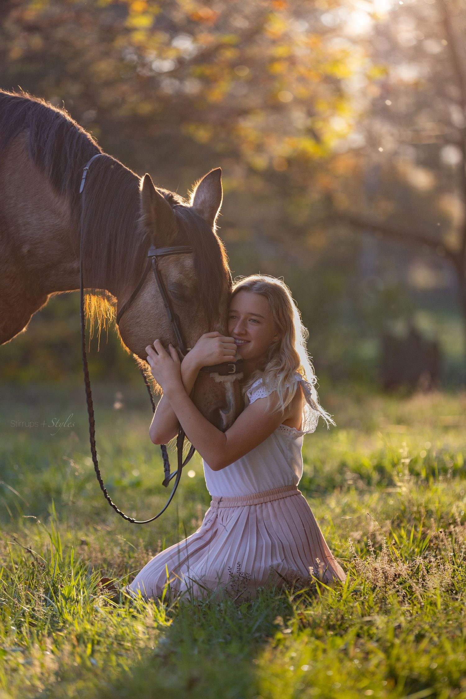 White dress-clad figure sits in sunlit meadow with horse illuminated by golden hour backlight in nature setting.