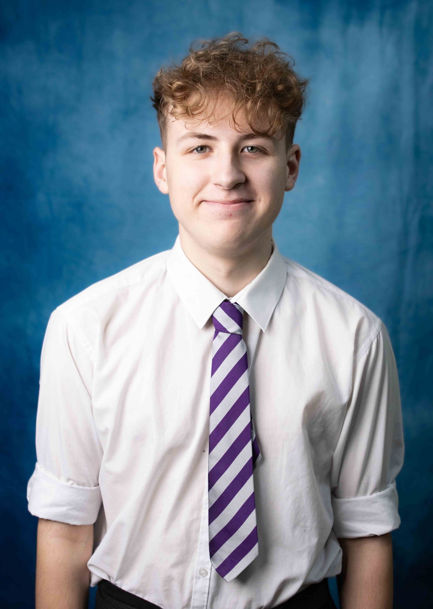Student in white school uniform shirt and purple striped tie poses against blue backdrop in series of yearbook photos.