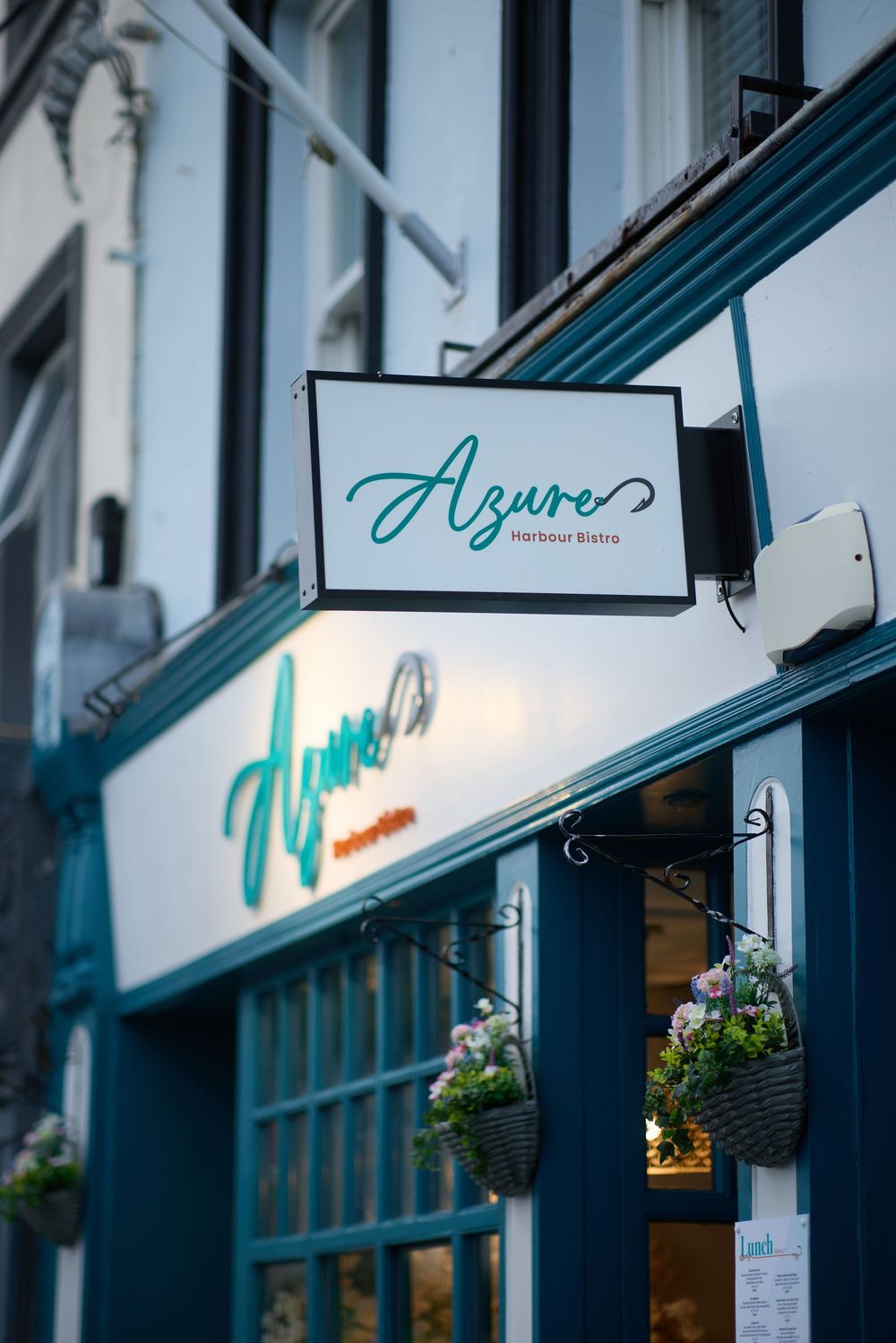 Exterior storefront signage with teal accents and illuminated lettering at dusk.