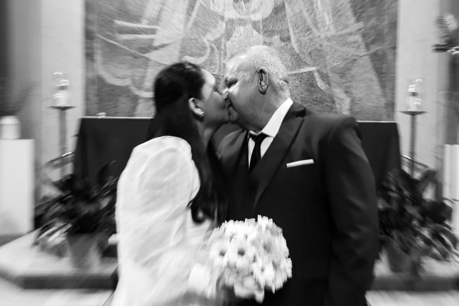 Black and white romantic church wedding photo shows couple sharing an intimate moment by the altar.