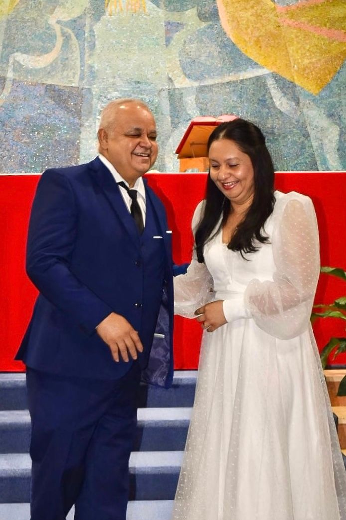 A joyful wedding ceremony moment captured in front of a colorful church mural.