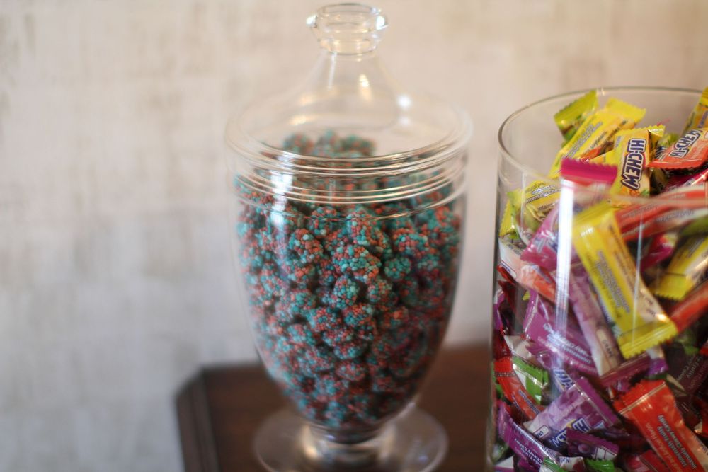 Glass candy jars filled with blue wrapped candies and colorful wrapped sweets on display.