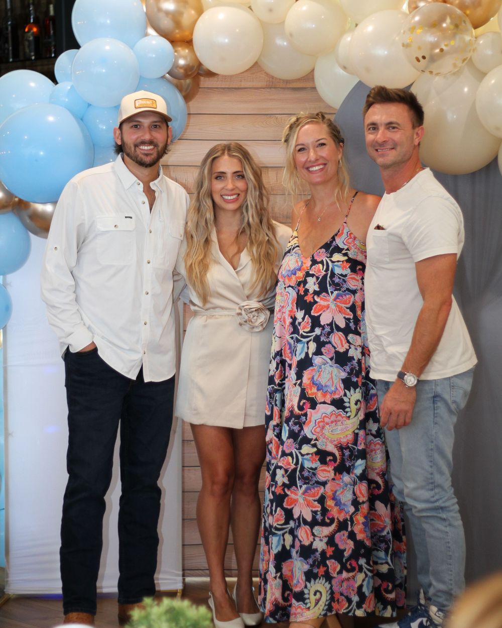 Party gathering with festive balloon arch featuring white and light blue balloons.