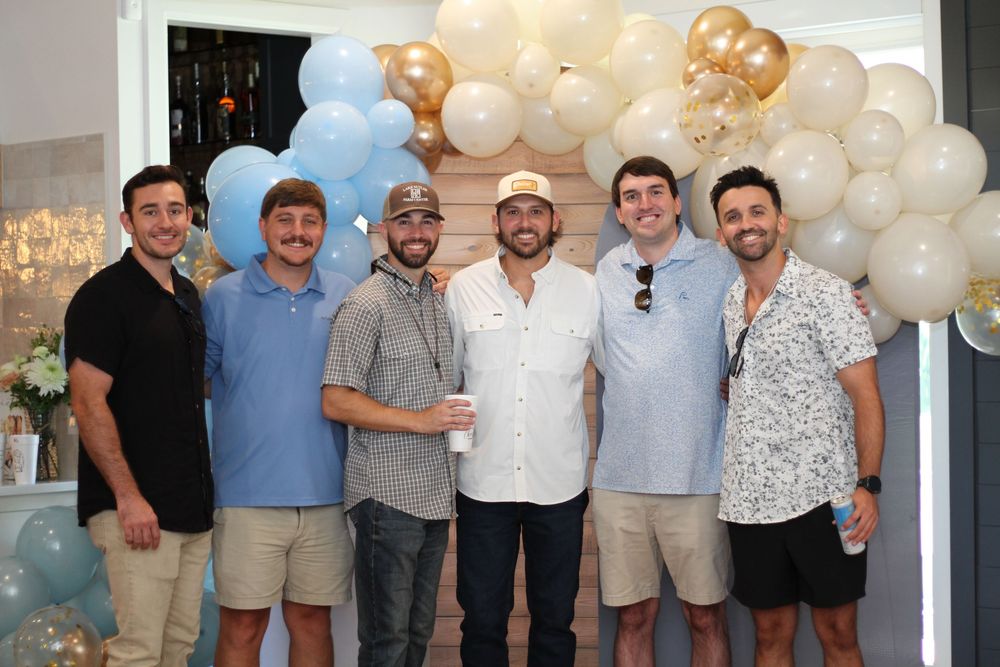 Group photo at a party with elegant balloon decorations and soft lighting.