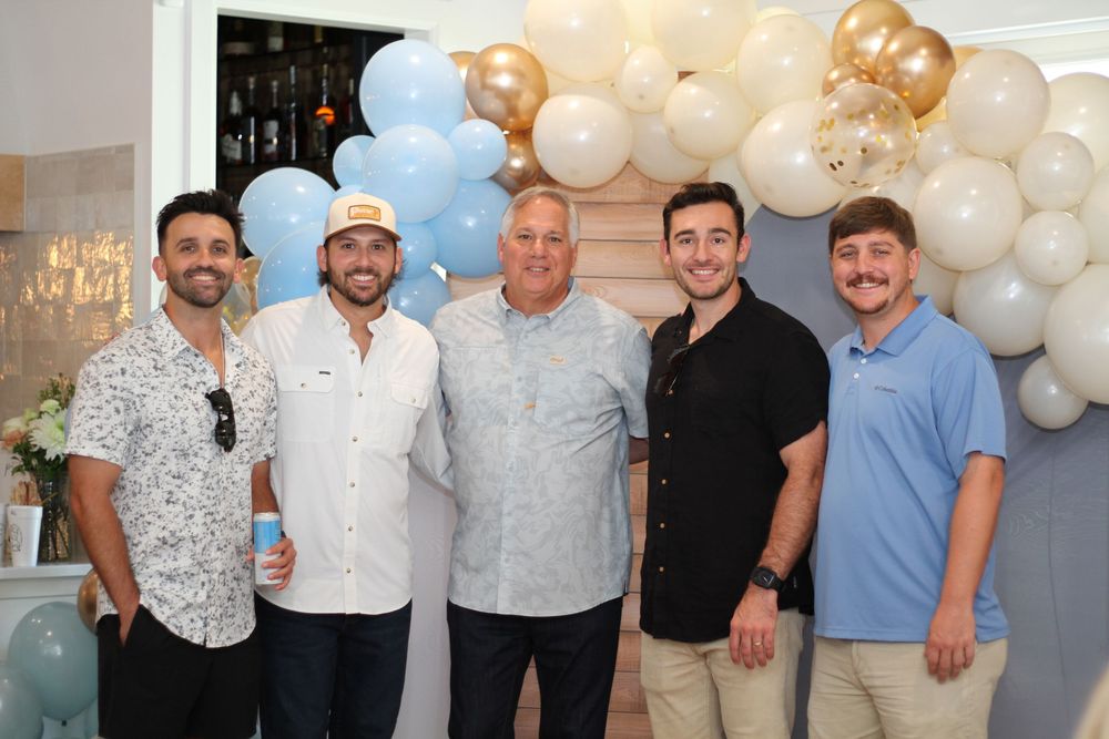 Group photo with white and gold balloon decorations at a celebratory event.