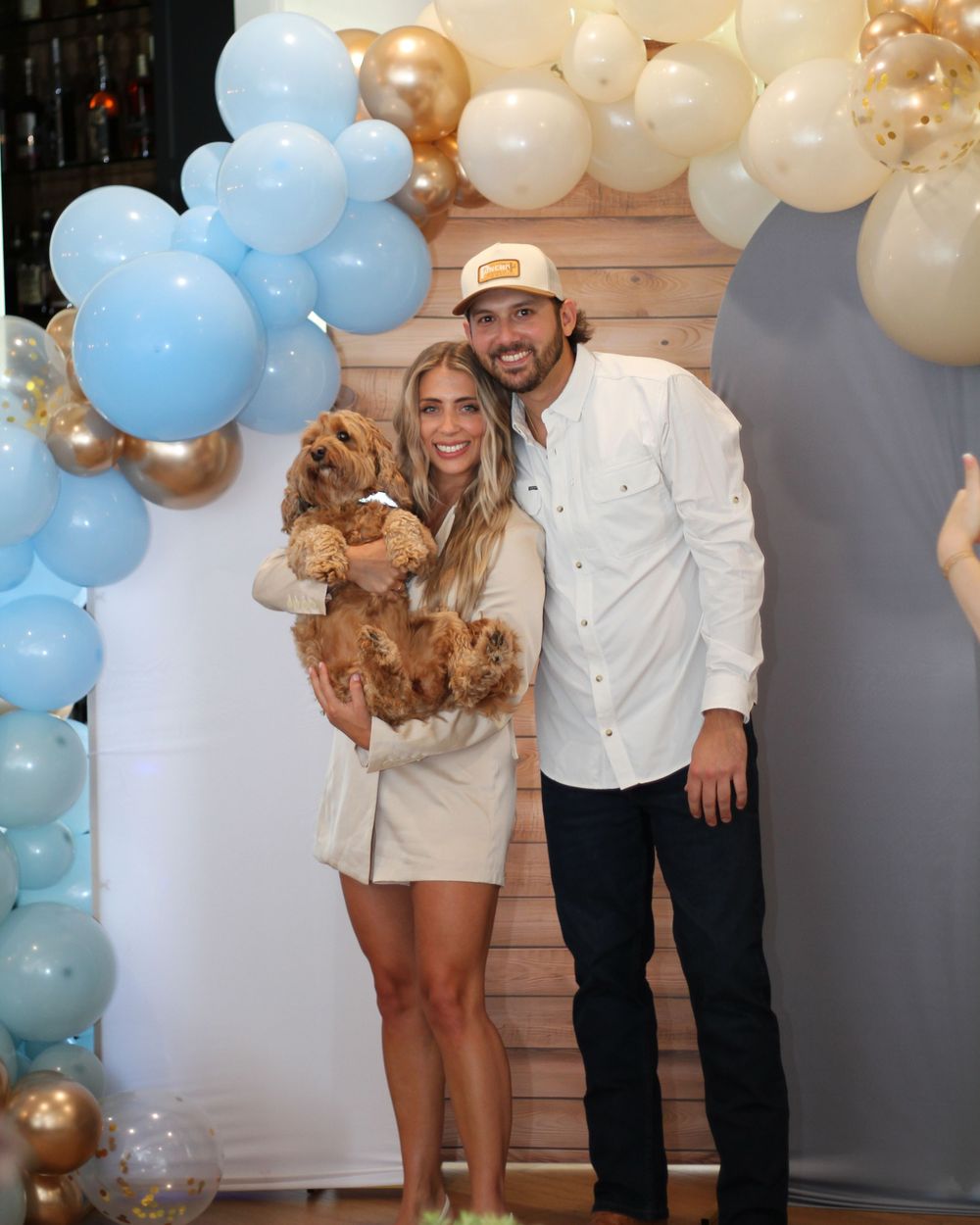 Party scene with blue and gold balloon arch decorations against a light colored wall.