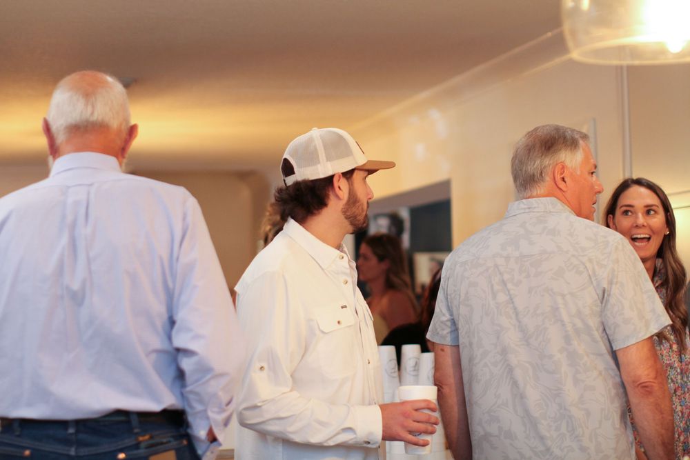 Group of people in white and light colored clothing gathered at a social event indoors.