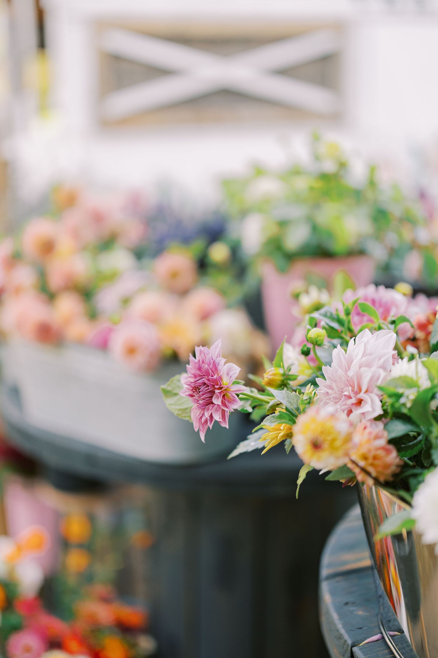 Beautiful arrangement of pink, peach and yellow dahlias and fresh greenery in soft focus.