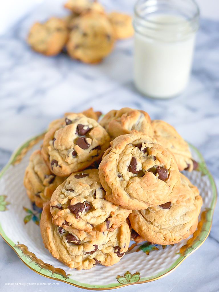 Chocolate chip cookies on a decorative plate with a glass of milk.