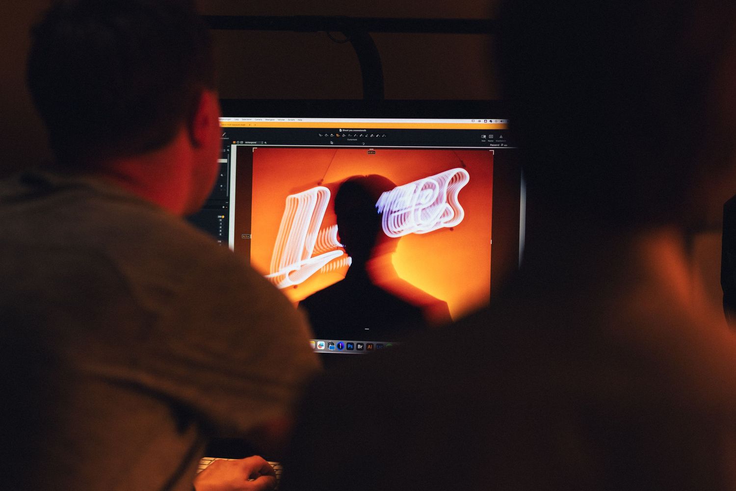 Person holds illuminated mobile device while browsing in dimly lit environment showing red and orange lighting.