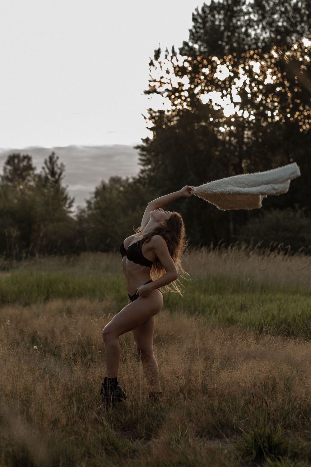 A silhouetted figure dances with flowing fabric in a misty field at sunset, creating a dreamy atmospheric scene.
