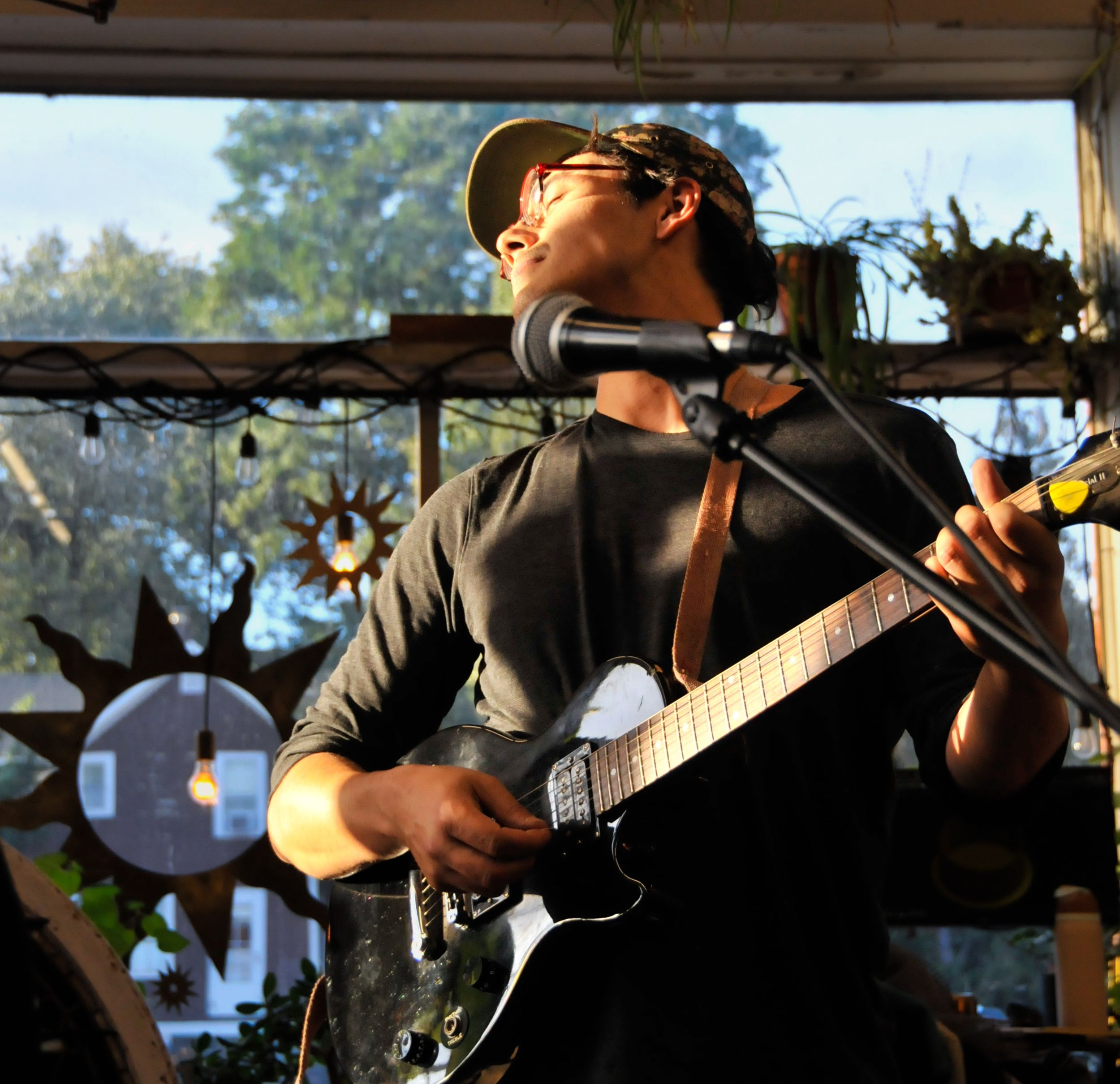 Man poses with guitar in golden hour light during portrait photography session.