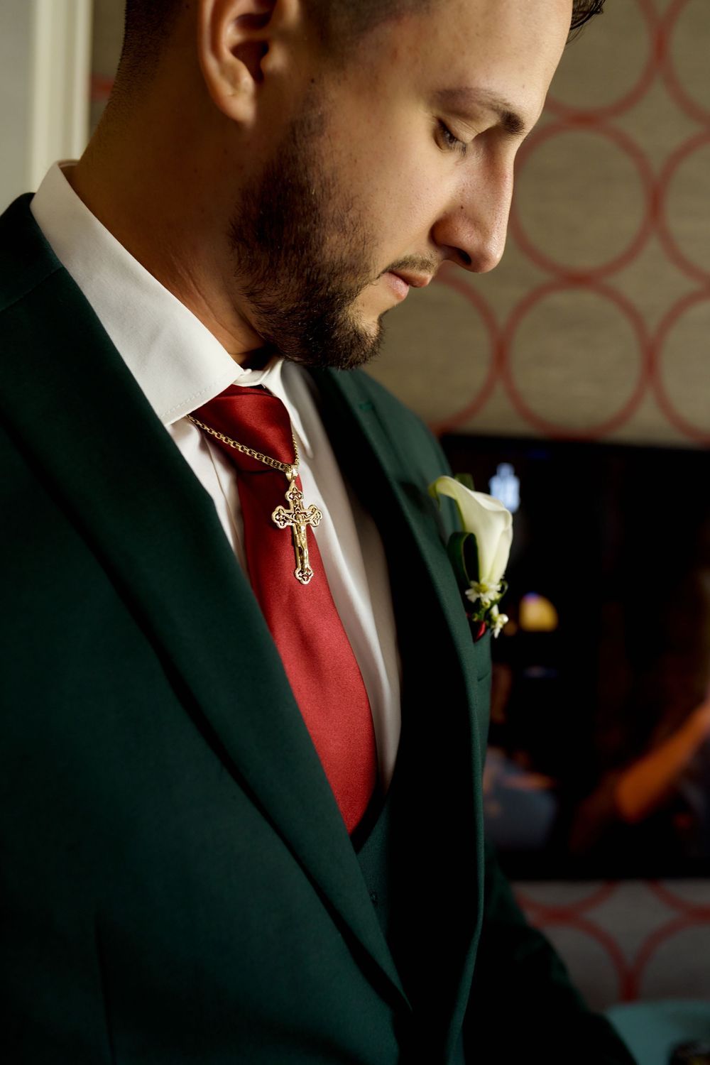 Side profile view shows a groom in an emerald green suit with burgundy tie and white boutonniere.