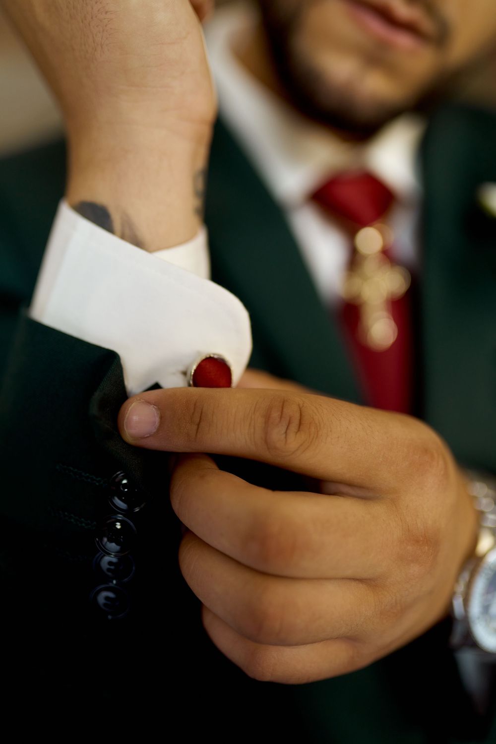 Close-up shot of hands adjusting a white collar in formal suit attire wedding day