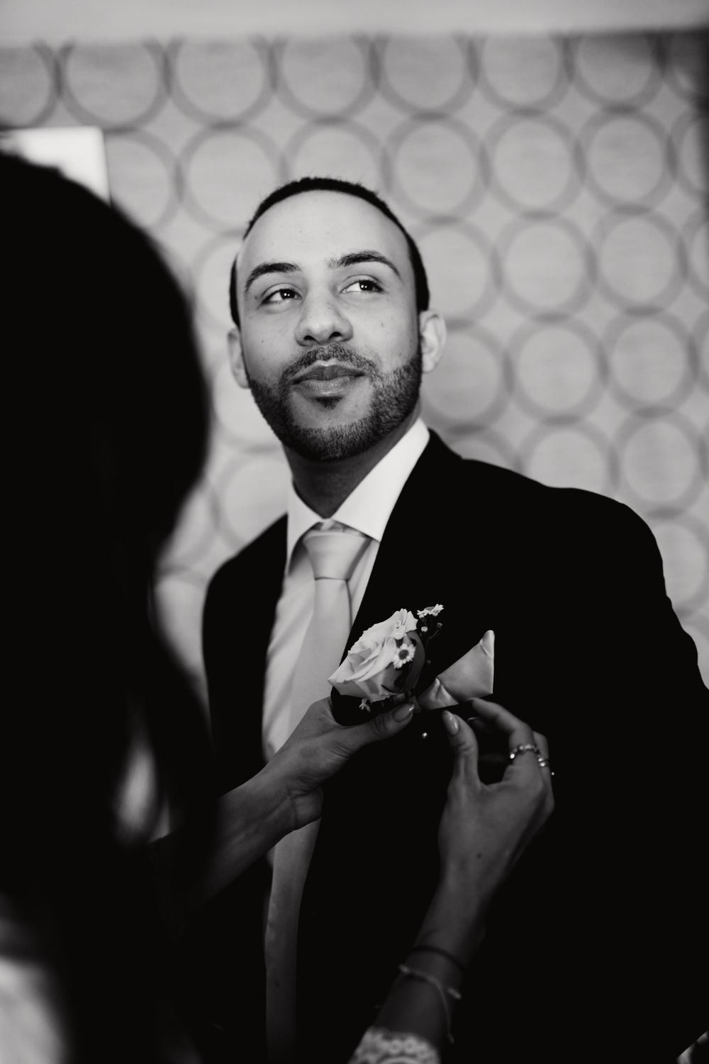 A series of black and white photos showing hands adjusting a tie and formal suit in preparation for an event.