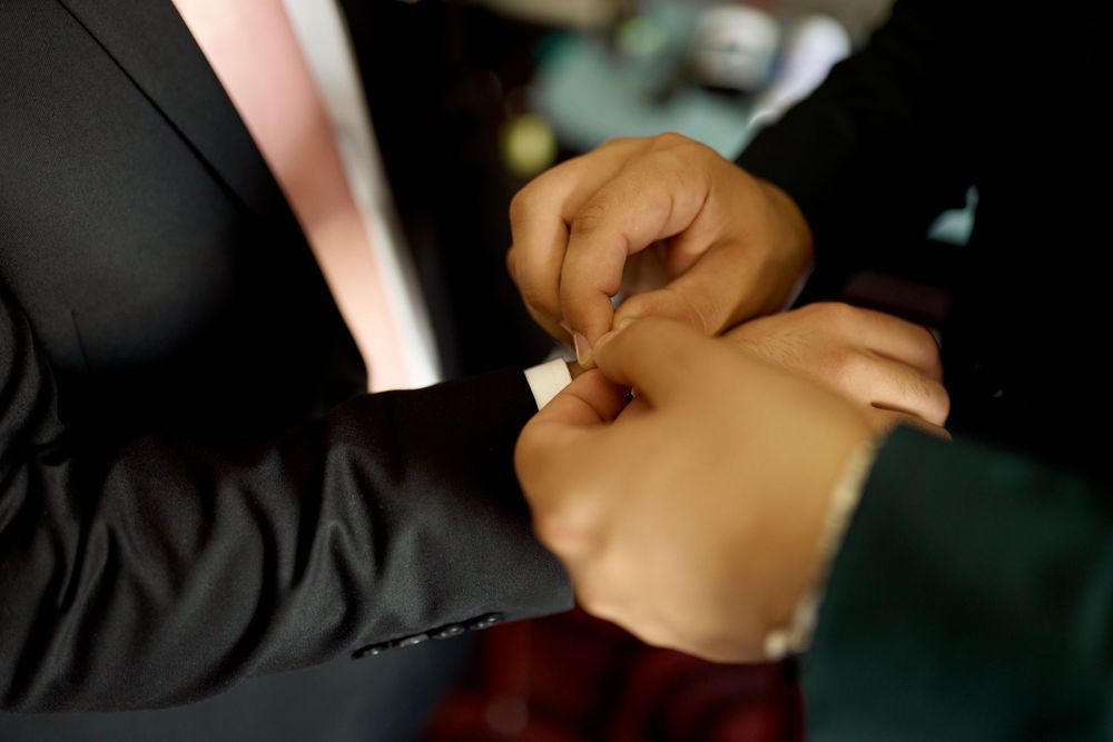 Close-up of best man helping the groom get ready in the hotel room on the day of the wedding
