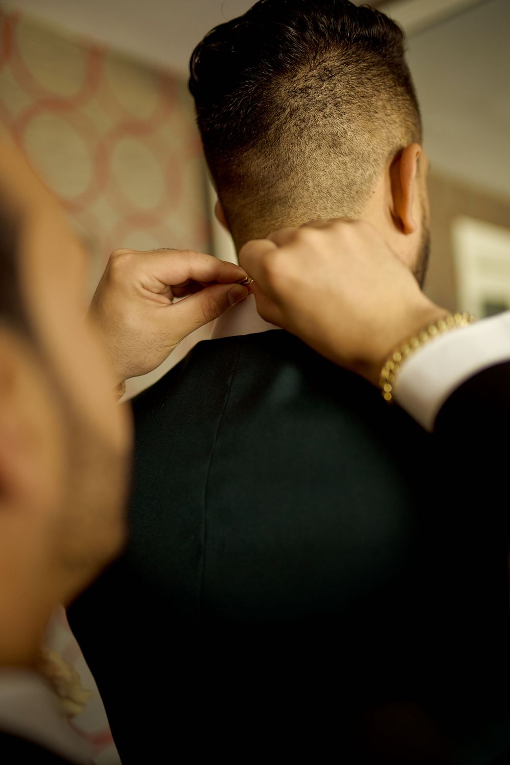 best man helping the groom get ready in the hotel room on the day of the wedding