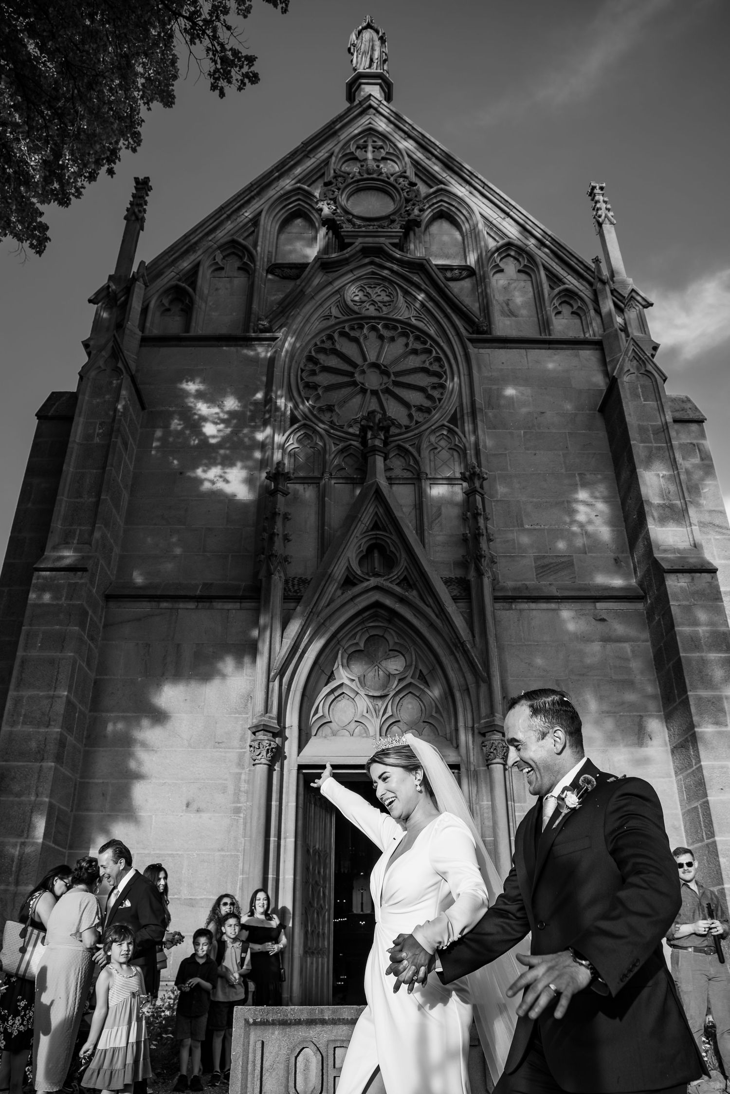 Gothic revival church exterior provides dramatic backdrop for wedding ceremony with ornate architectural details.