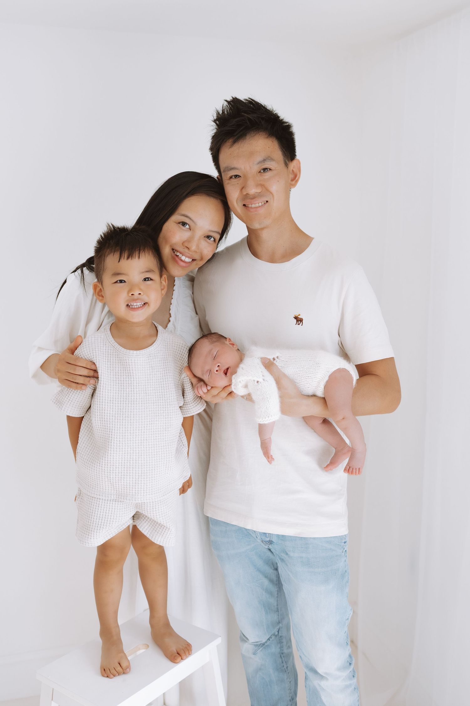 Happy family in white outfits sharing playful moments against a white background in a series of casual portrait photos.