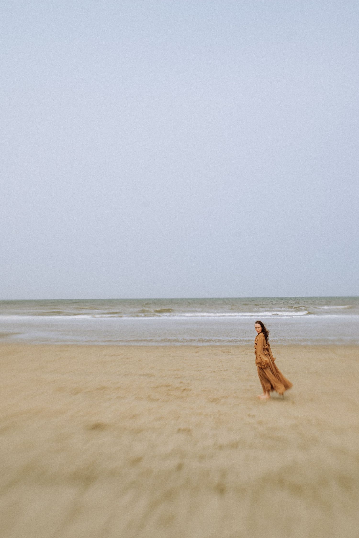 Romantic woman in a flowing dress on a wide open seaside in the Netherlands.