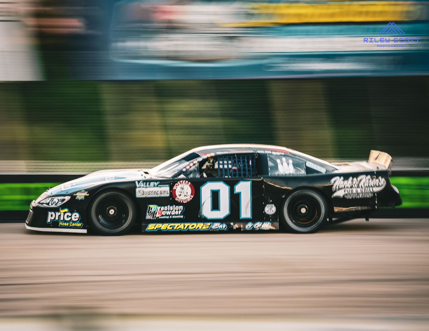 Motion blur effect of a black racing car speeding along a racetrack during a motorsport competition.
