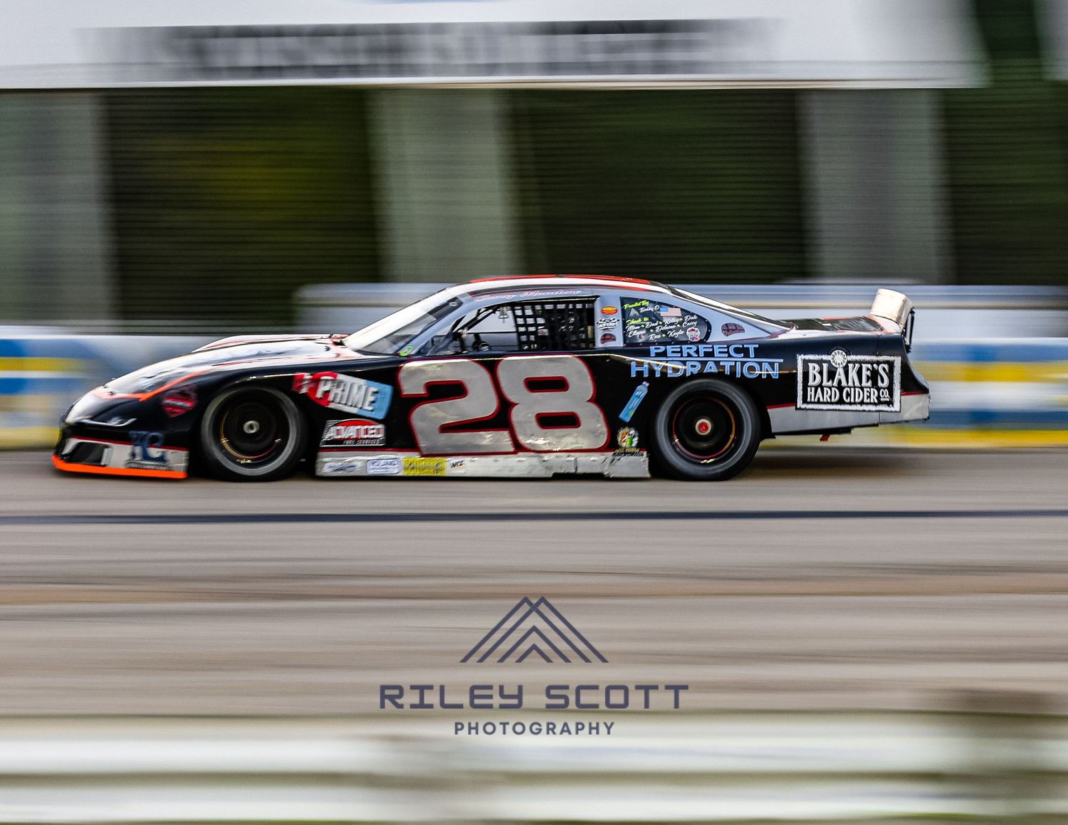 A race car speeds past on a professional racing track with motion blur creating a dynamic effect.