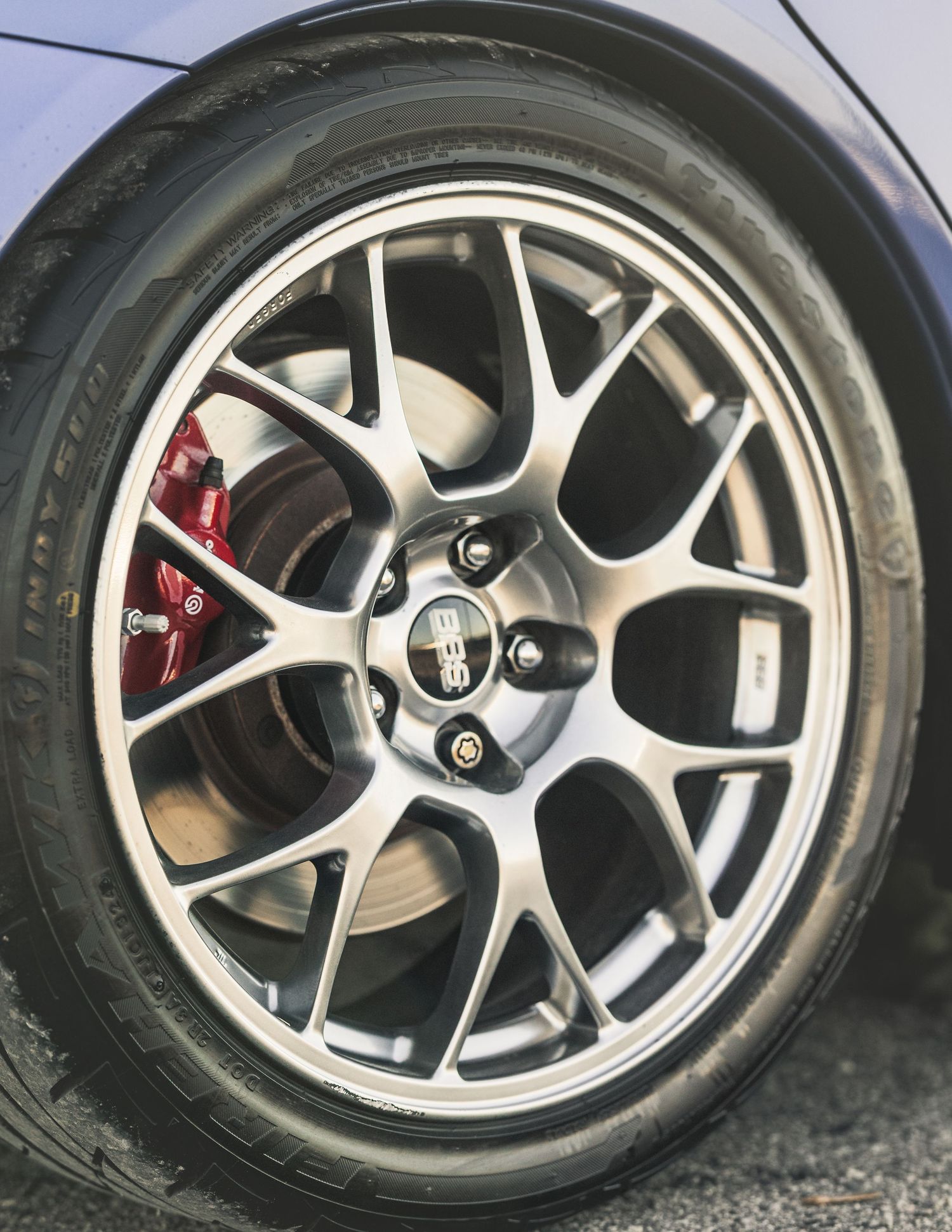 Close-up of a silver multi-spoke alloy wheel with red brake calipers on a performance sports car tire.