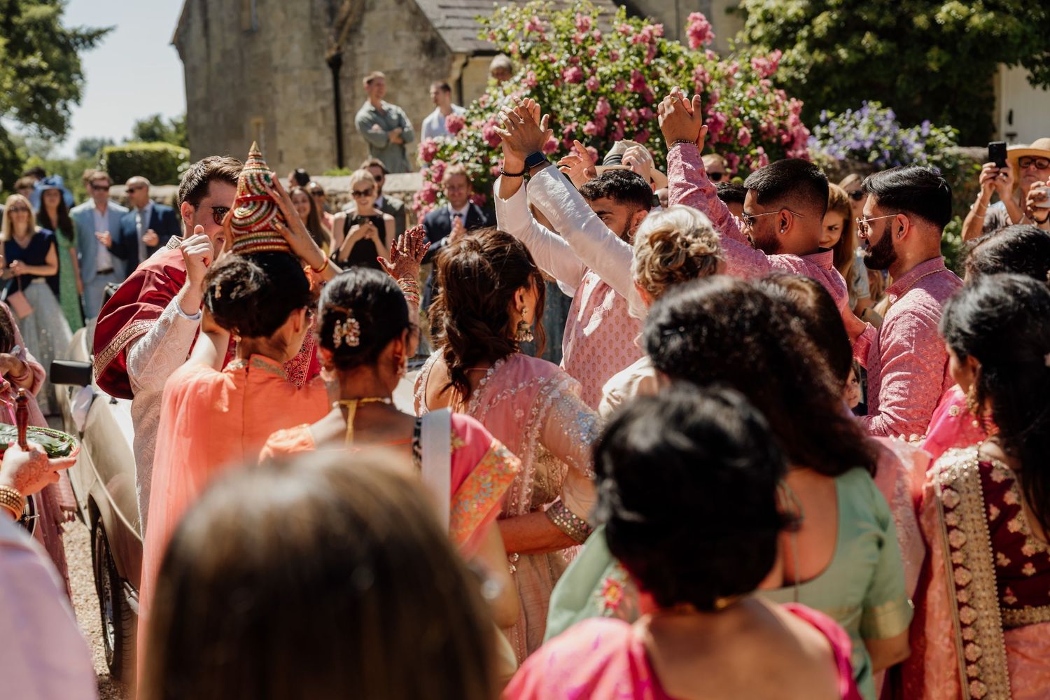 Festive wedding celebration with guests showering pink petals in an outdoor ceremony.