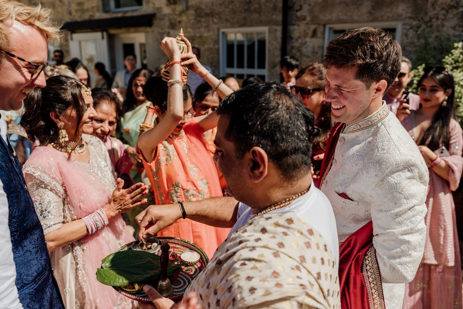 Wedding guests gather outdoors for a celebratory toast with drinks in hand during a festive garden reception.
