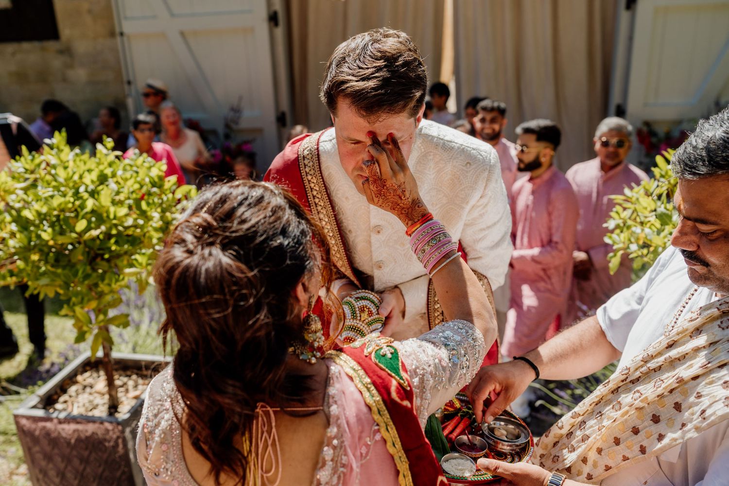 Outdoor wedding celebration with guests in traditional formal attire dancing in a courtyard.