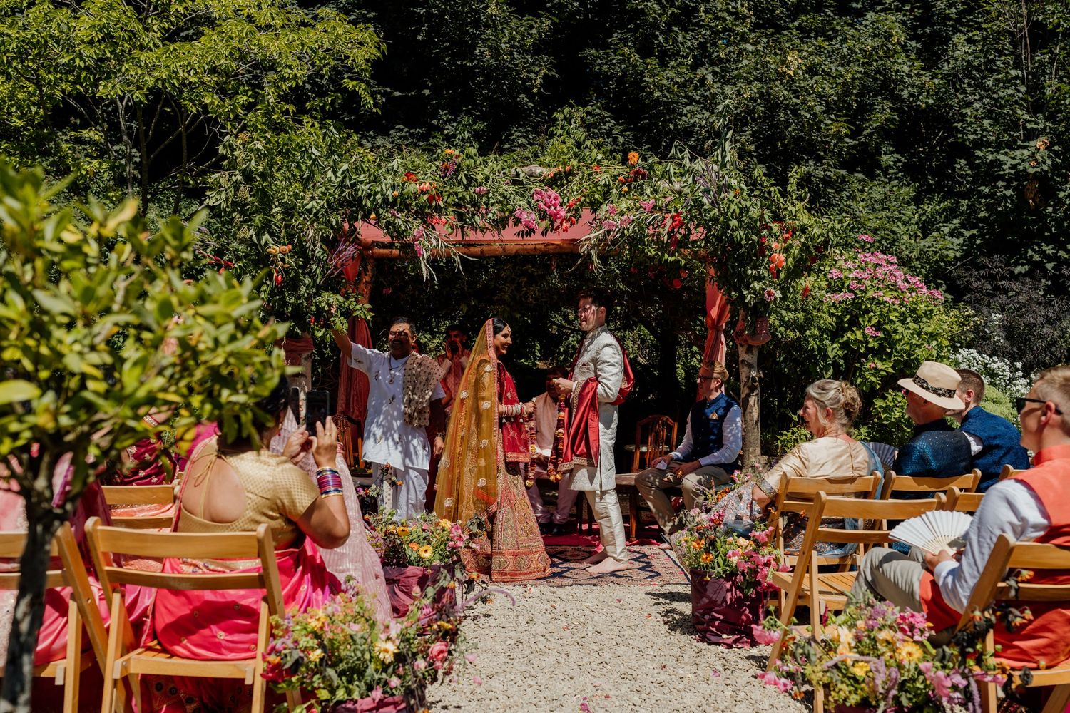 Wedding guests mingle and celebrate in a garden setting with traditional decorations.
