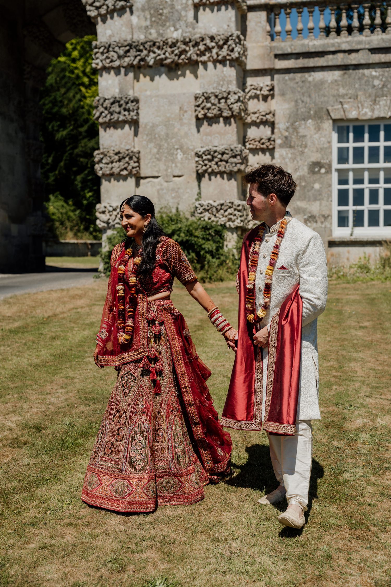 Traditional South Asian wedding formalwear displayed in an elegant outdoor setting against historic architecture.