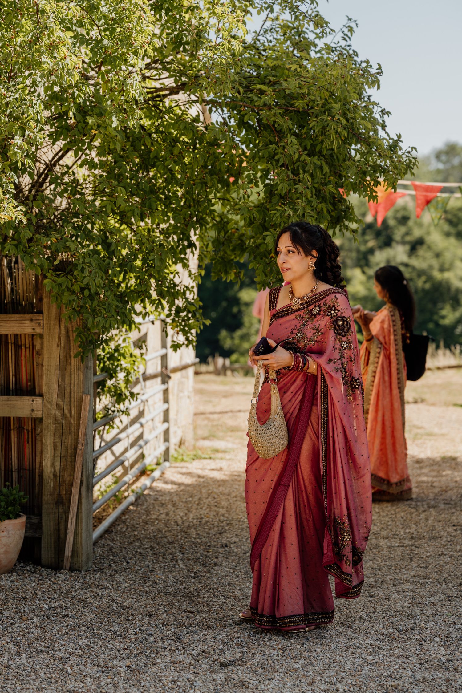 A sequence of outdoor bridal portraits under green trees showing flowing red and gold traditional Indian attire.
