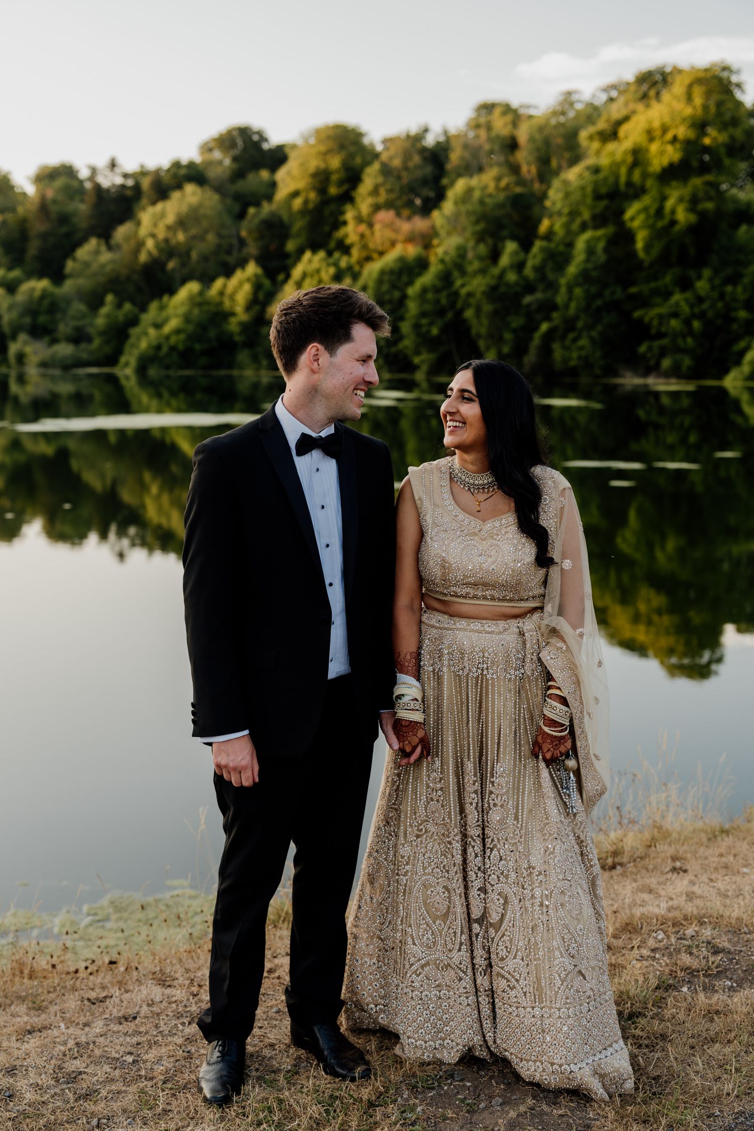Waterfront wedding portrait session with couple in formal attire along a serene lake.