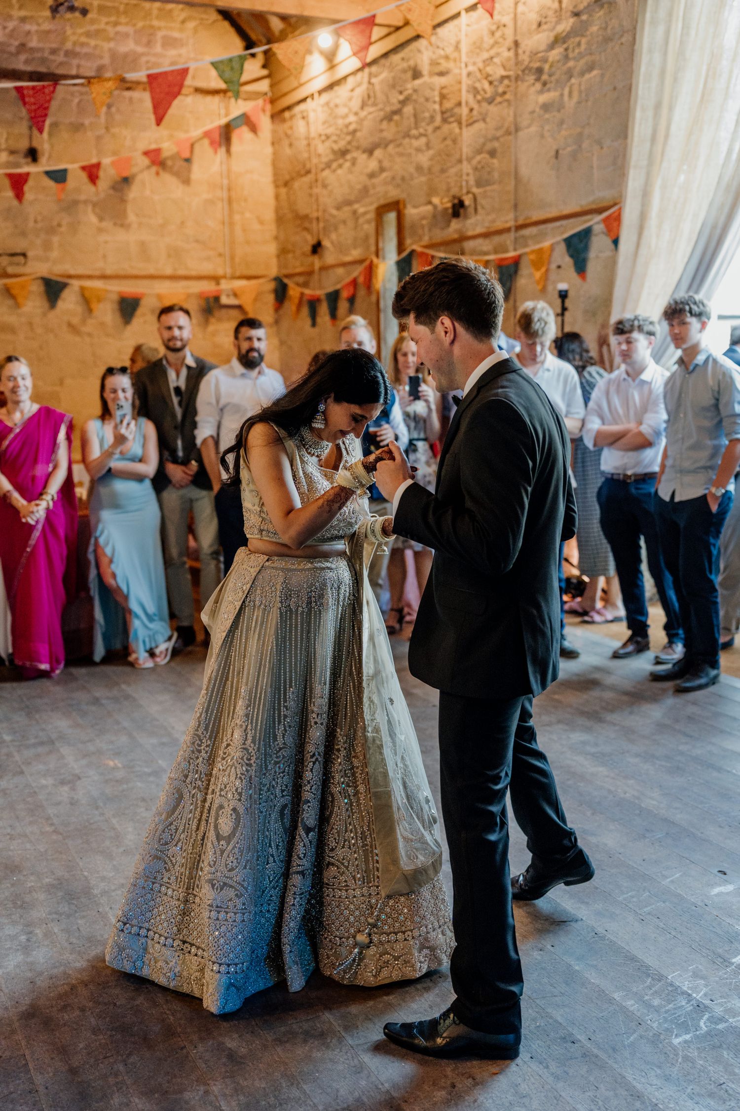 Elegant wedding reception in a rustic stone venue decorated with colorful bunting flags.