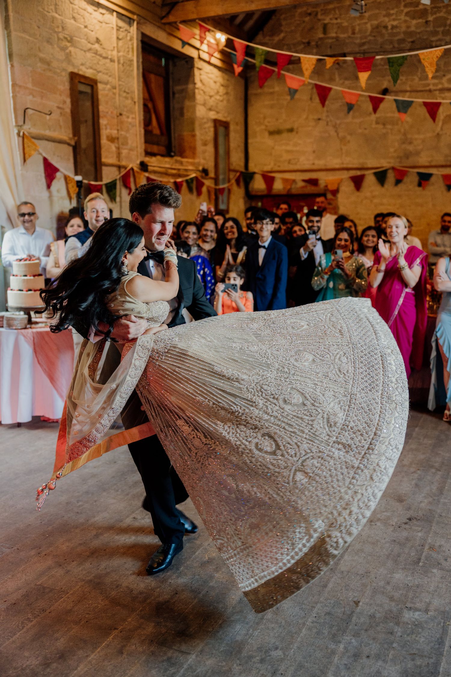 A couple spins and dips on a rustic stone dance floor decorated with festive bunting flags during a celebration.