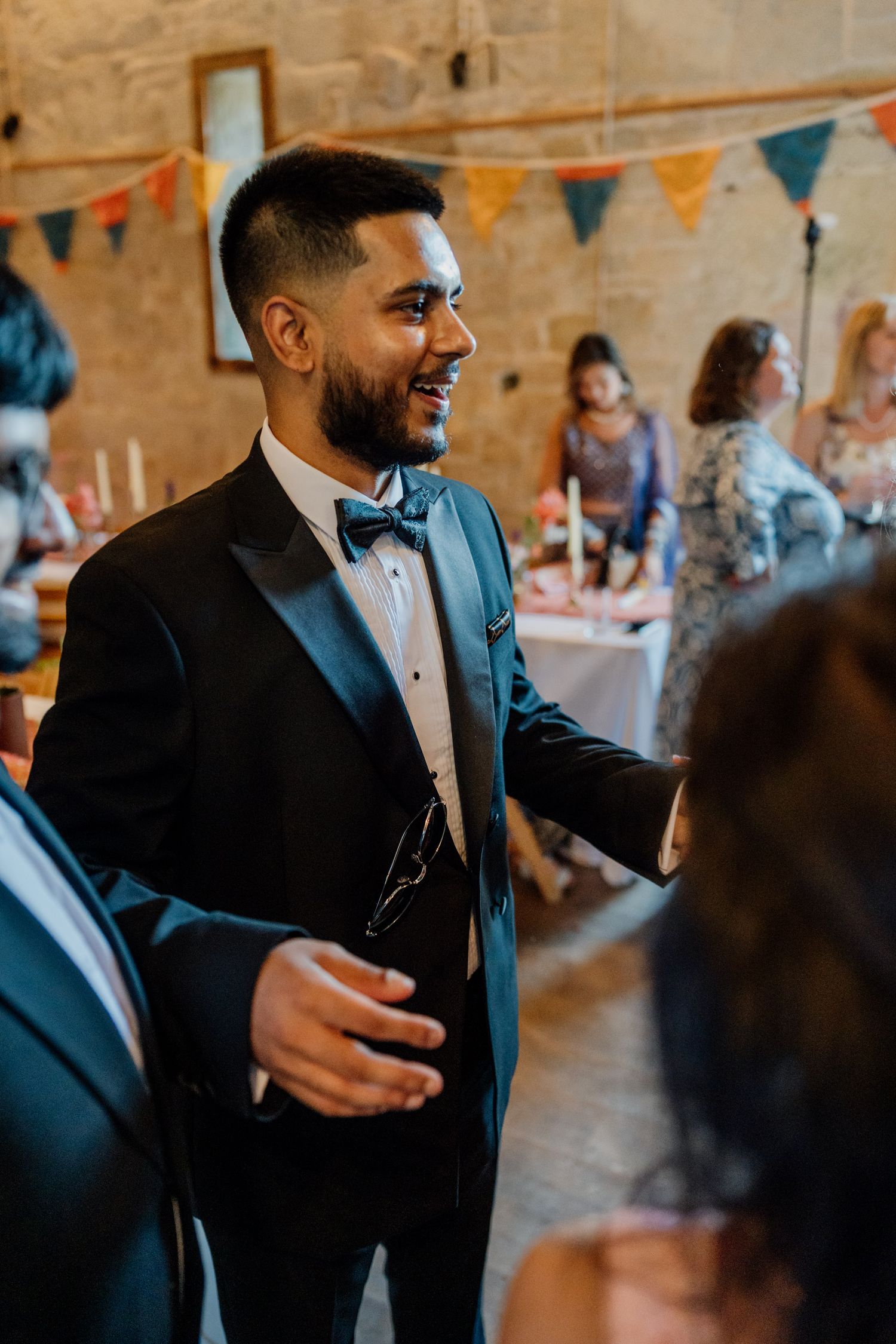 A celebration takes place inside a rustic venue decorated with colorful bunting flags.