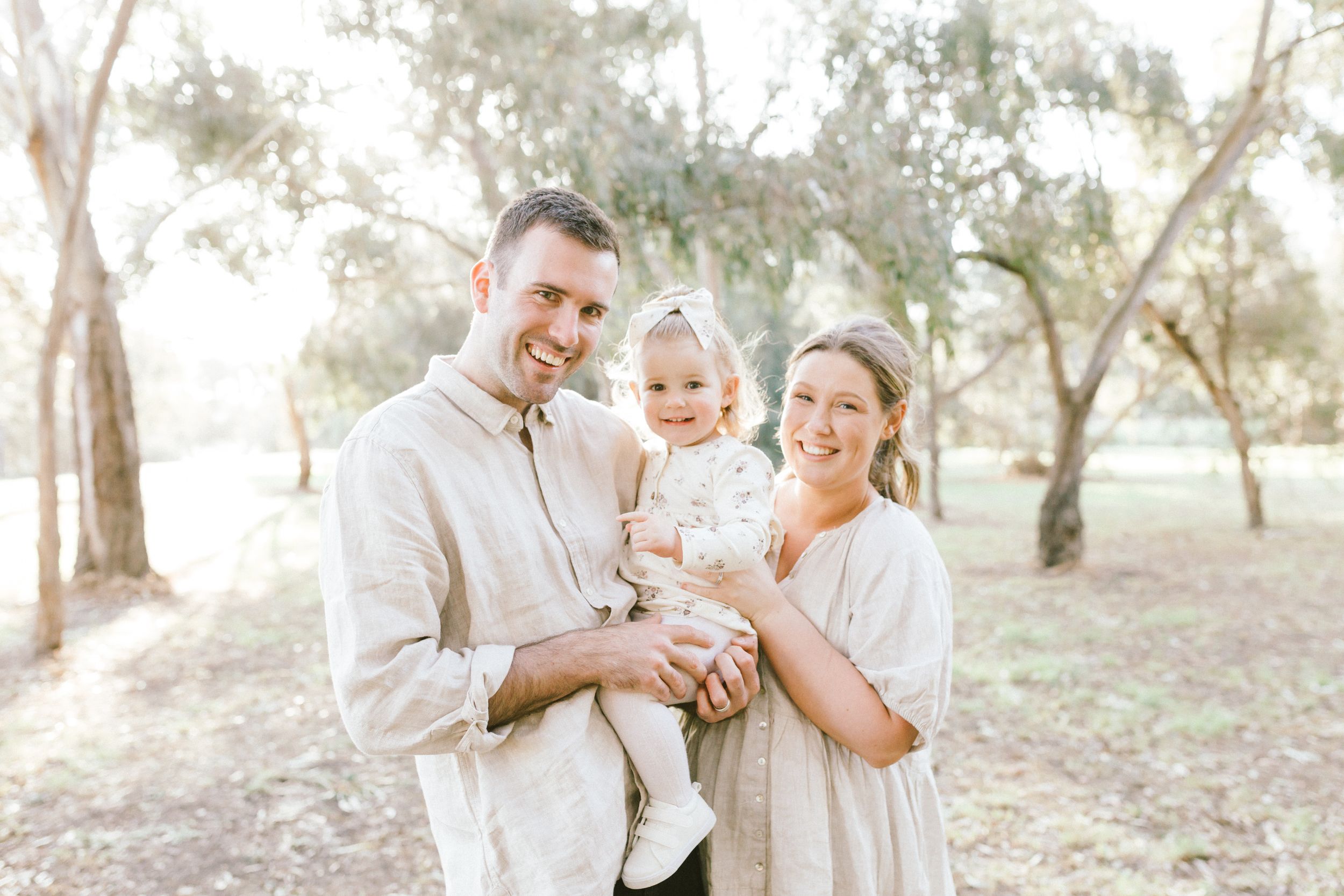 A sweet family gathering in a sun-dappled olive grove with bright natural lighting and casual attire.