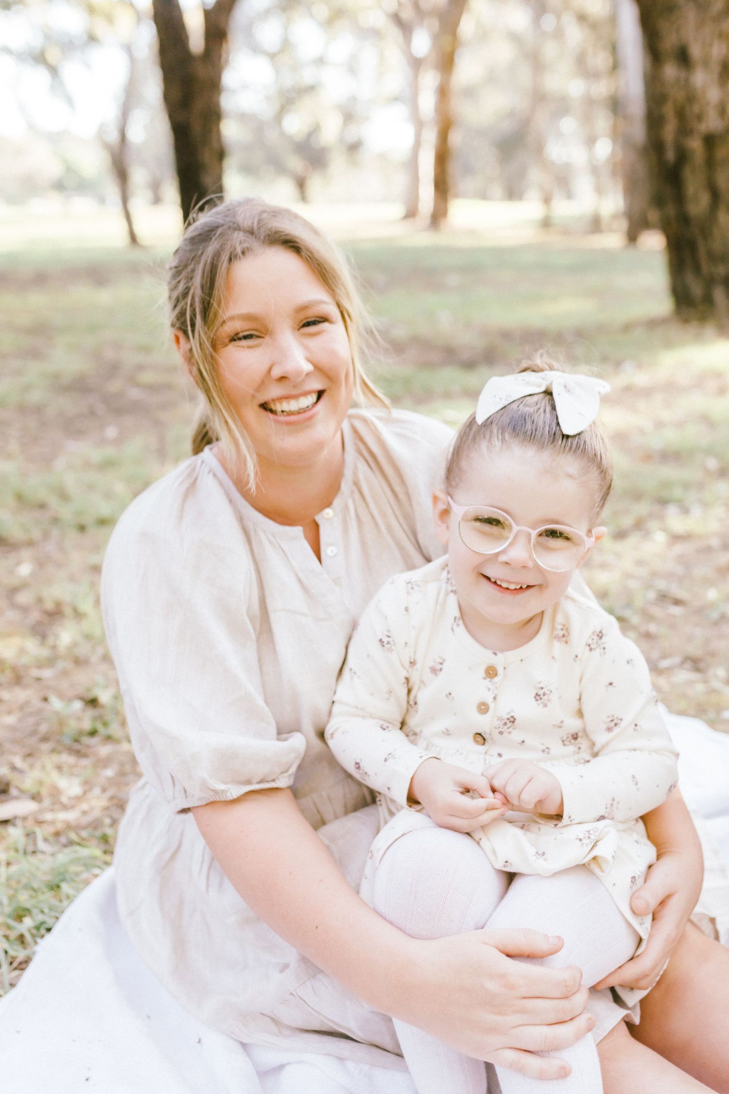 A series of outdoor photos showing tender moments in matching white outfits against a wooded backdrop.